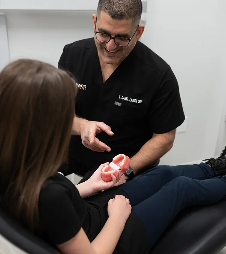 Dr. Daniel Lawen, DDS smiling with young patient over a plastic model of teeth